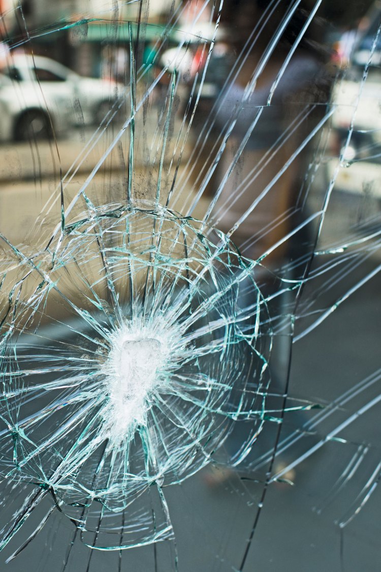 Shattered glass pane with cracks spreading from the impact point
