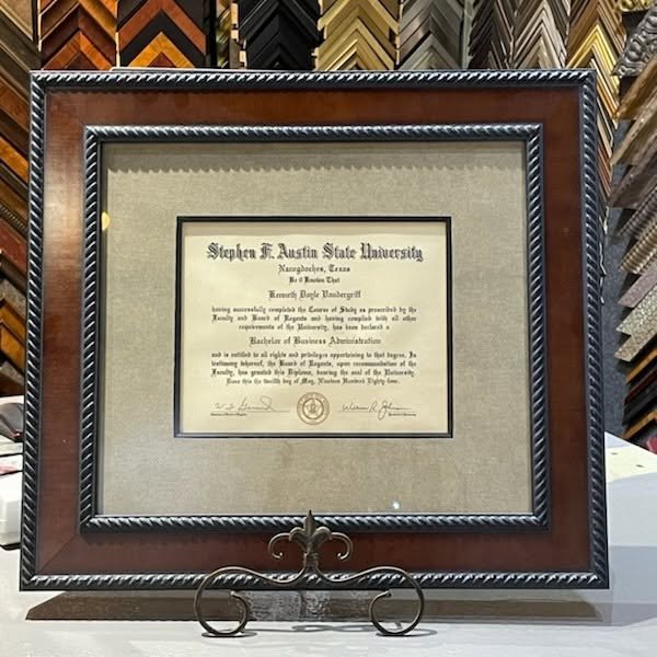 University diploma in a matted wood frame on a stand