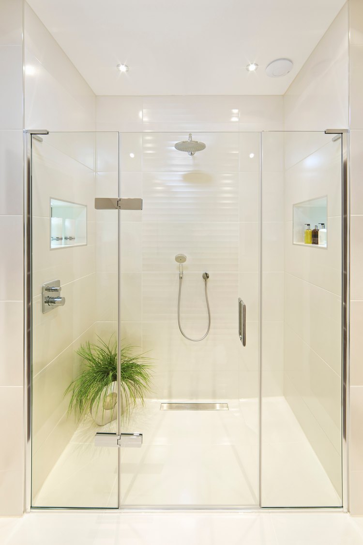 Frameless glass shower enclosure in a white bathroom