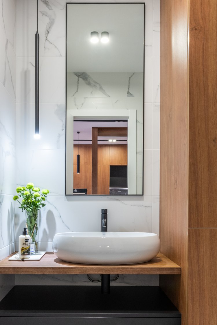 Tall mirror above a wood bathroom vanity with vessel sink
