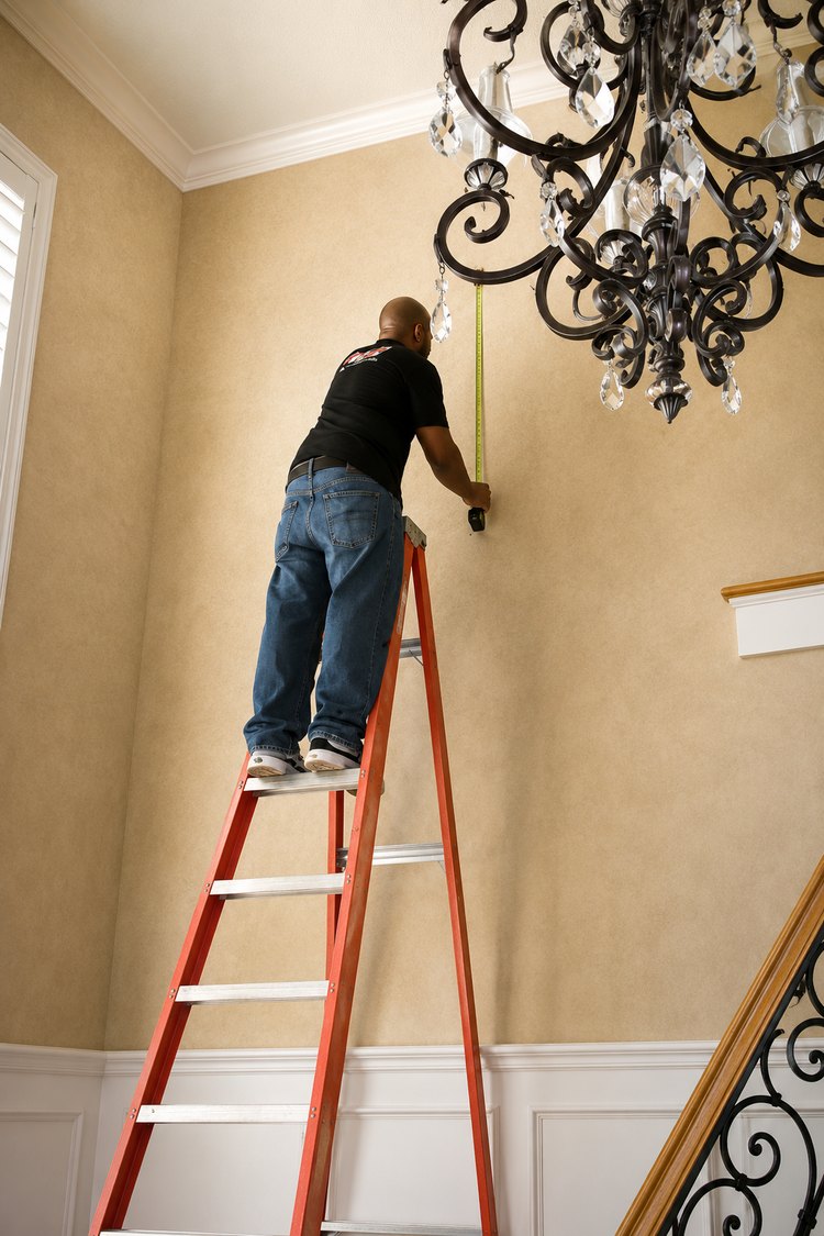 Installer on a ladder hanging a frame in a stairwell