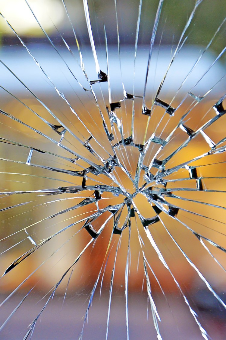 Shattered window pane with cracks radiating outward